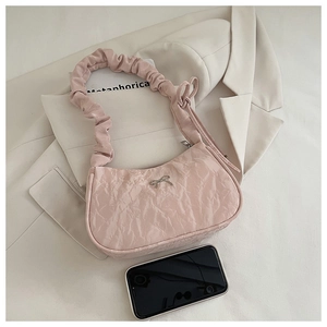 Detail of pink pleated crescent bag with silver bow and smartphone for scale reference