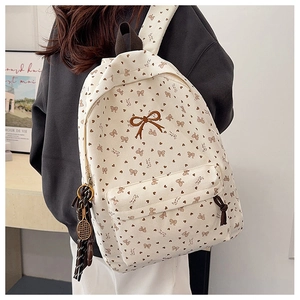 Detail eines Cord-Rucksacks mit gestickter Schleife und Tennis-Anhänger-Zubehör