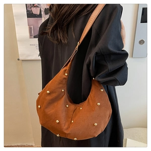 Dettaglio ravvicinato della borsa hobo in camoscio marrone con borchie dorate