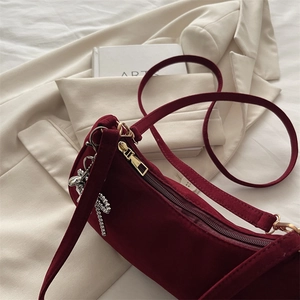 Deep red velvet underarm bag with gold zipper and bear charm on beige blazer
