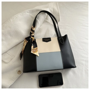 Detailed close-up of tri-color tote bag with leather tag and decorative silk scarf