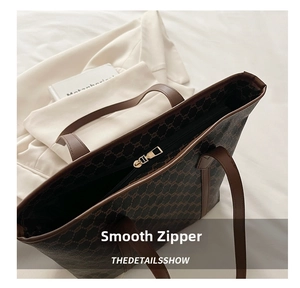 Detailed close-up of smooth gold metal zipper on luxury monogram tote bag texture
