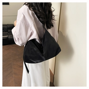Vista laterale macro di una grande borsa hobo a mezzaluna in nylon nero indossata da una modella