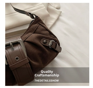 Detail of vintage brown suede bag featuring oversized metal buckle and distressed leather