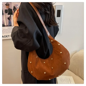 Borsa hobo in pelle scamosciata marrone con borchie dorate indossata a spalla