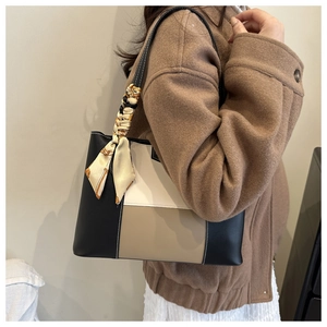 Detail of color-block tote bag with elegant silk scarf on handle worn over the shoulder
