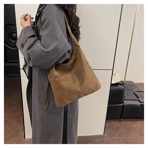 Close-up of vintage brown suede shoulder bag with decorative stitching on a model