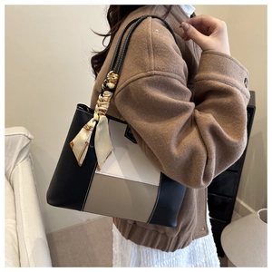 Detail of color-block tote bag with decorative silk scarf on handle and matte finish