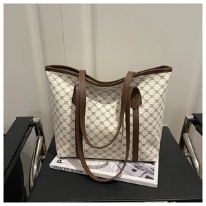 Close-up of geometric monogram canvas tote bag with brown leather trim on a modern black chair