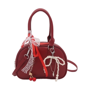 Sac Boston rouge foncé avec nœud en dentelle et pendentifs cerises sur fond blanc