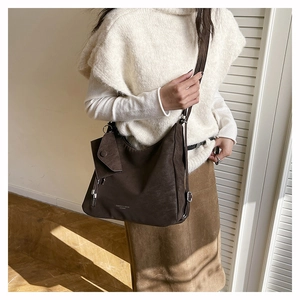 Gros plan du sac bandoulière marron rétro montrant la texture mate et le texte gravé