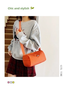 Détail du sac cylindrique orange en nylon quadrillé avec bandoulière réglable tissée