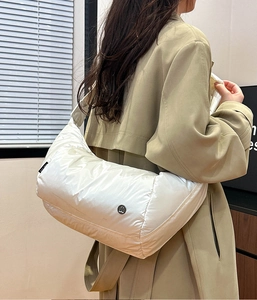 Dettaglio della borsa trapuntata bianca con etichetta nera e logo circolare in metallo