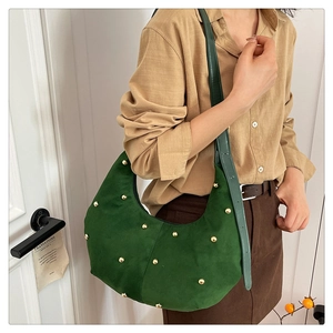 Dettaglio della borsa hobo in camoscio verde scuro con borchie dorate e tracolla in pelle