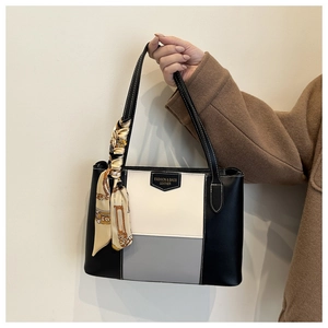 Detail van de kleurblok shopper met metalen logo, witte stiksels en zijden sjaal