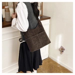 Detail view of large brown tote bag with white contrast stitching and dual front pockets