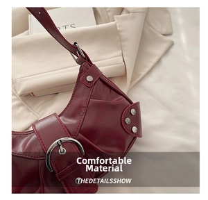 Close-up of vintage burgundy shoulder bag with large silver buckle and rivet details