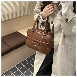 Detail view of a vintage brown leather tote bag with a metallic heart charm and bow accent