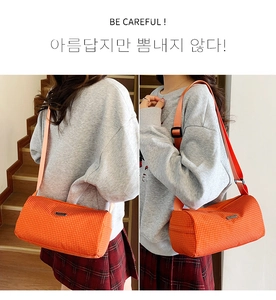 Détail du sac bandoulière cylindrique en nylon orange à carreaux avec sangle réglable