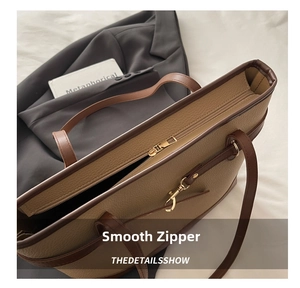 Detail shot of khaki leather tote bag featuring a smooth top zipper and golden hardware buckle