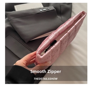 Close-up of smooth metal zipper on pink quilted puffer nylon cosmetic clutch bag