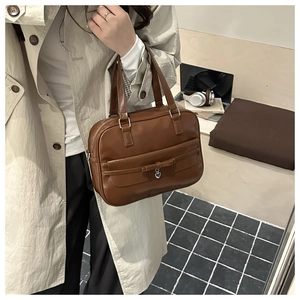 Detail of vintage brown tote bag with leather bow and heart pendant in a lifestyle setting