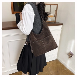 Detail of a large dark brown hobo bag featuring white contrast stitching and matte texture