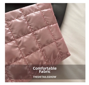 Close-up of pink quilted fabric with glossy waterproof finish on a large clutch bag