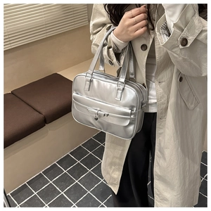 Close-up of metallic silver Boston bag featuring a 3D bow and heart-shaped metal pendant