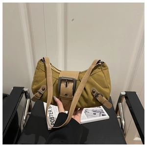 Detail of green canvas hobo bag featuring large vintage metal buckle and brown leather strap