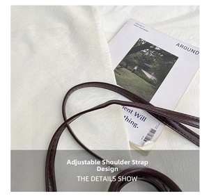Detail of adjustable shoulder strap with neat stitching on deep brown leather mini bag