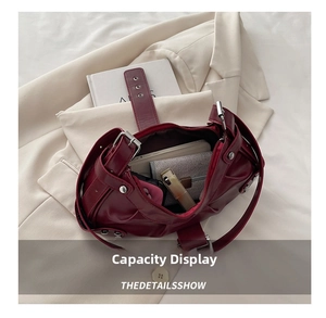 Detail of dark red pleated underarm bag showing interior capacity with silver buckle