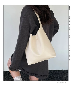Vue détaillée du grand sac cabas vintage crème avec logo doré porté à l'épaule
