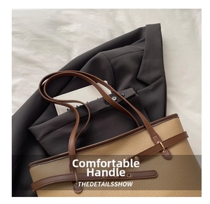 Detail of lychee pattern leather tote bag with brown trim and metal buckle on suit jacket