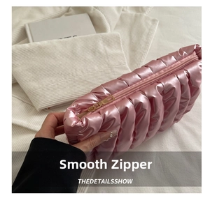 Detail of pink pleated satin pouch with a smooth golden metal zipper and quilted texture