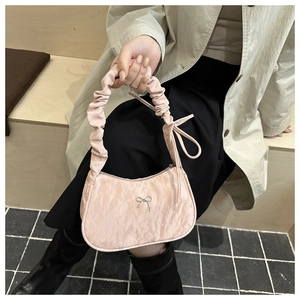 Close-up of pink pleated fabric handbag with silver bow detail and ruched handle