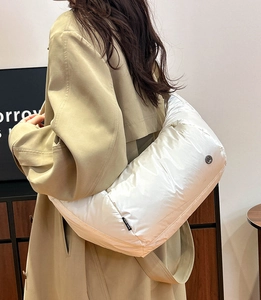 Dettaglio di una borsa a tracolla trapuntata bianca lucida su un trench color kaki