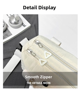 Detail view of smooth dual zippers with ergonomic pulls on a cream nylon crossbody bag