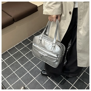 Detail of silver metallic tote bag with decorative bow and magnetic flap pocket
