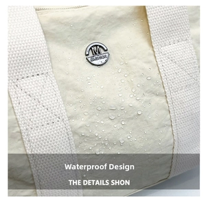 Detail shot of beige nylon bag surface showing water-resistant drops and metal logo