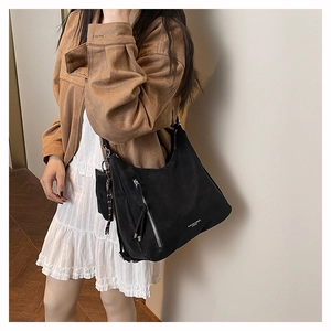 Detail of black nylon tote bag with functional vertical zippers and small side pouch charm