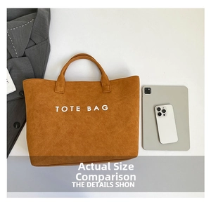 Top-down view of a tan faux suede tote bag with white TOTE BAG print and tech accessories