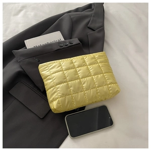 Flat lay of a yellow quilted makeup bag with square stitching on white fabric