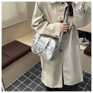 Silver metallic Boston bag worn over a beige trench coat with chic bow charm detail