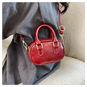 Detail of red glossy leather mini boston bag with embossed logo and gold hardware