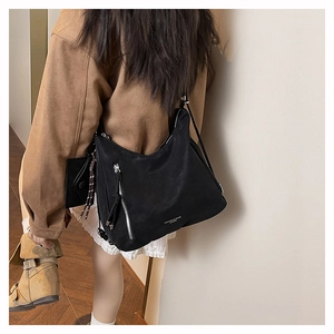 Detail of black hobo bag with metal zipper tassel shown from a stylish side-back angle