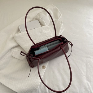 Sac bandoulière bordeaux foncé avec nœud latéral et intérieur spacieux pour essentiels quotidiens