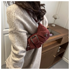 Detail of burgundy suede shoulder bag with pleated texture and retro metal buckle