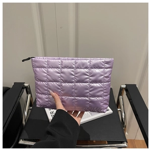 Close-up of purple puffer quilted makeup bag held by a person showing nylon texture