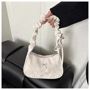 Close-up of white pleated ruched handbag with silver metal bow and scrunched handle